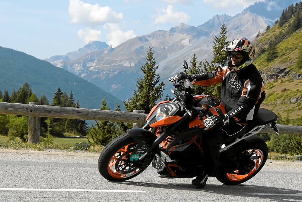 Motard sur une moto KTM orange dans les Alpes